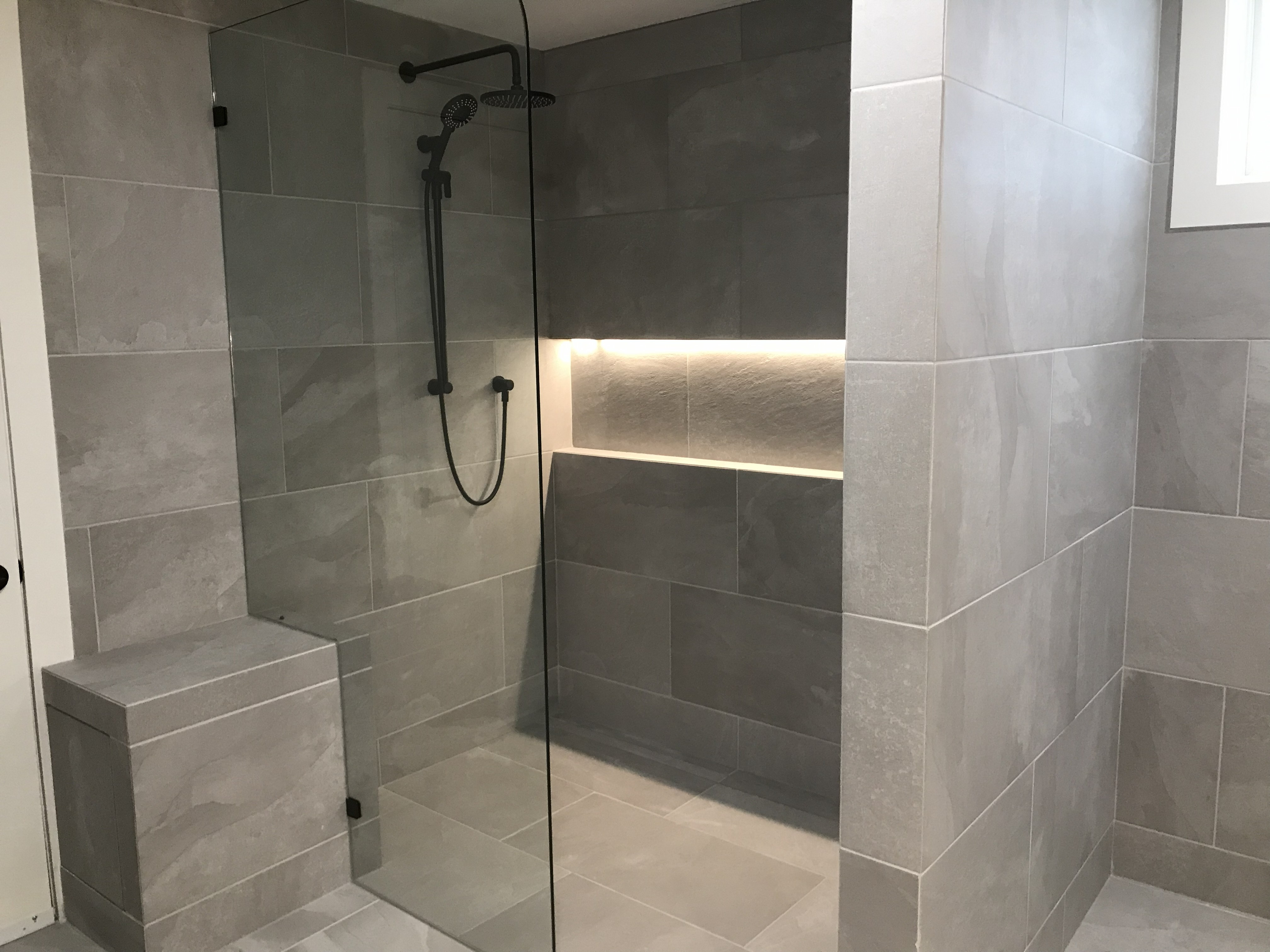 Walk-in shower with LED niche and bench — large format grey tile